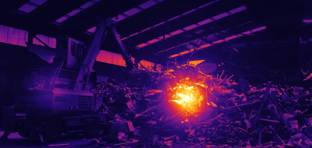 The same scene through a thermal camera, with one hot spot on the waste pile